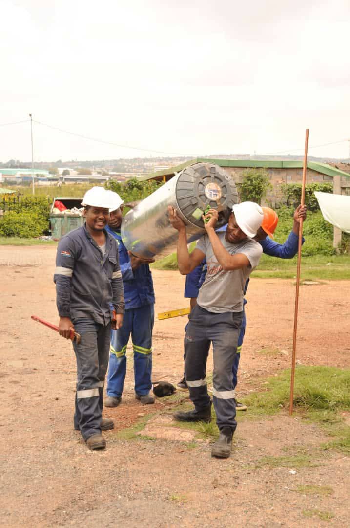 Team carrying a large water heater across a job site